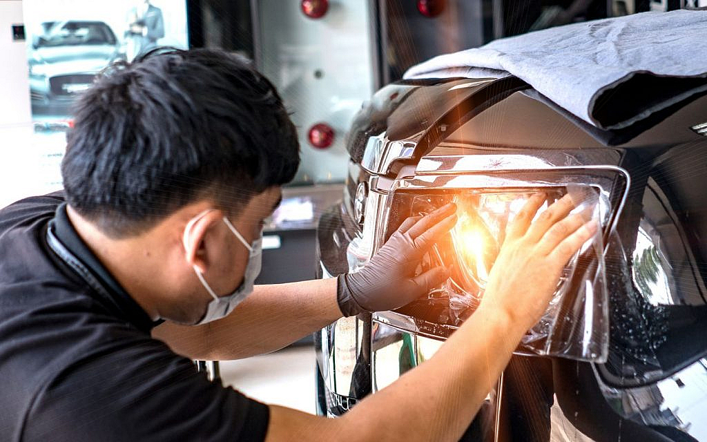 A mechanic is repairing the headlight of a car.