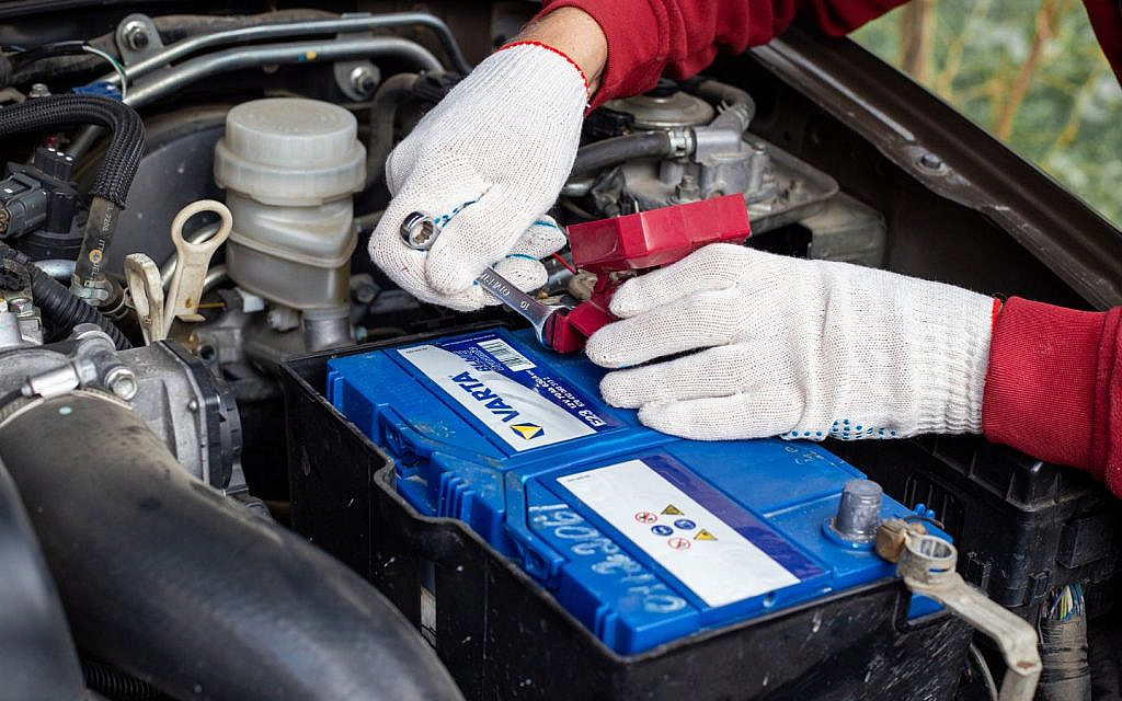 Mechanic wearing white gloves repairing car headlight.