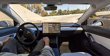 Tesla Model S interior with driver using Full Self-Driving features.