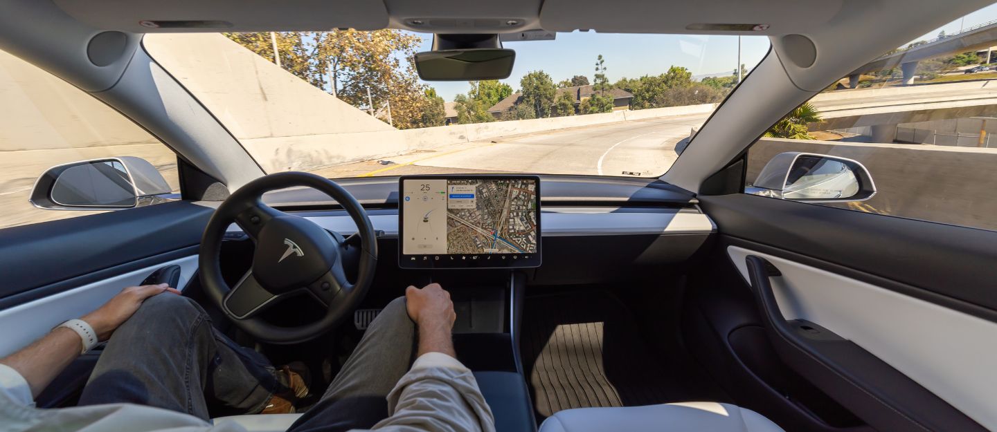 Tesla Model S interior with driver using Full Self-Driving features.