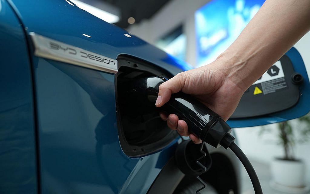 شخص يقوم بشحن سيارة بي واي دي زرقاء