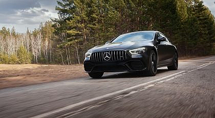 A Mercedes-Benz car is driving smoothly on a rough road.