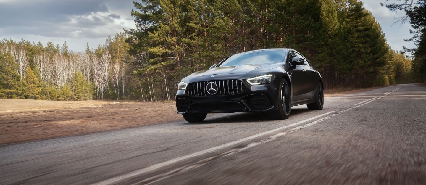 A Mercedes-Benz car is driving smoothly on a rough road.