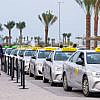 A line of Abu Dhabi Taxi App accessible taxis under an open sky, ready to provide transportation services.