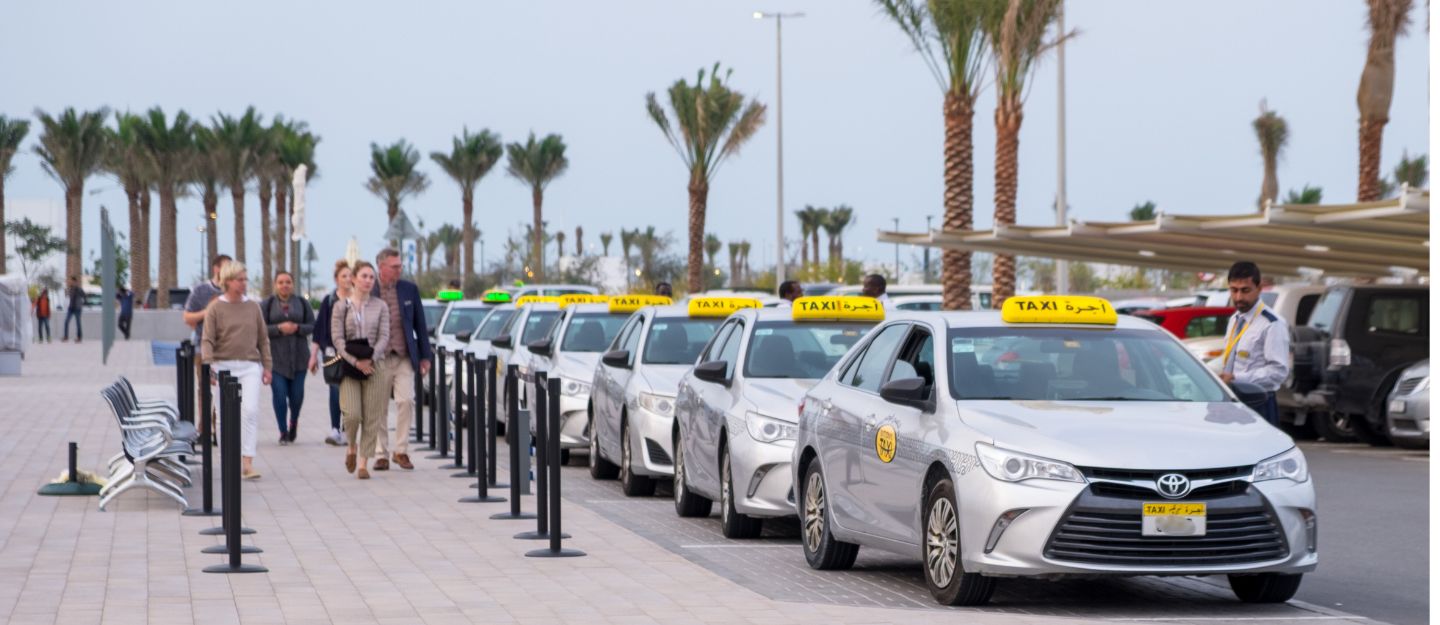 A line of Abu Dhabi Taxi App accessible taxis under an open sky, ready to provide transportation services.
