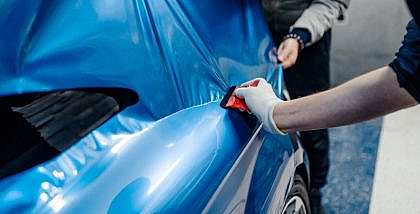 Pros and Cons of Car Wrapping - A Specialist applying thin foil to a car.