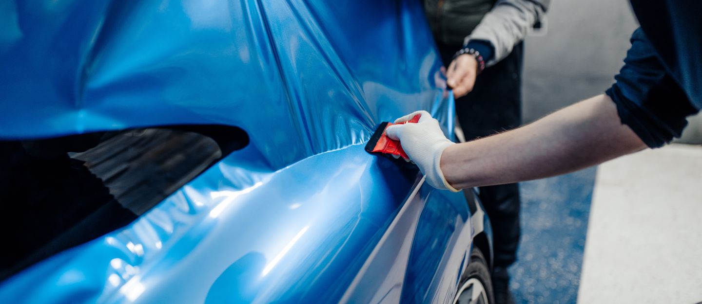 Pros and Cons of Car Wrapping - A Specialist applying thin foil to a car.