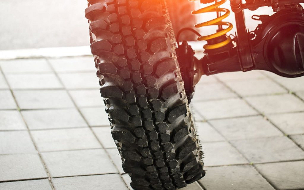 Car leaning on rugged surface, showing the signs of suspension misalignment.