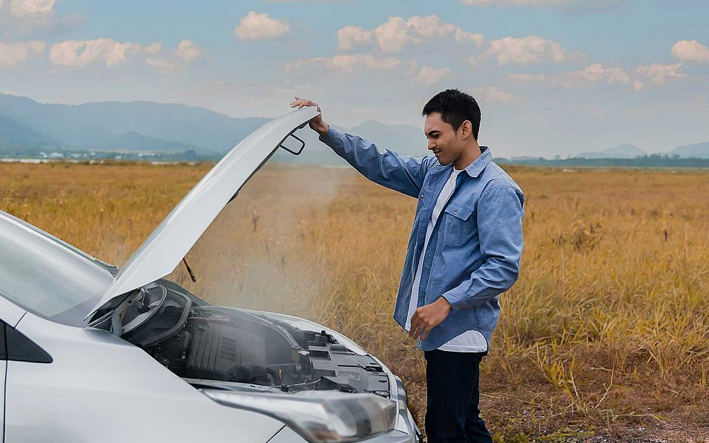 شخص يفحص سيارة يخرج منها دخان ابيض