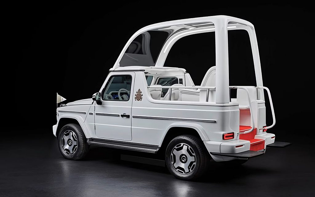 Electric Mercedes G-Wagon modified as the Popemobile with a glass enclosure and Vatican emblem.