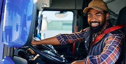 Smiling truck driver in the driver's seat, representing the journey to become a truck driver in Dubai.