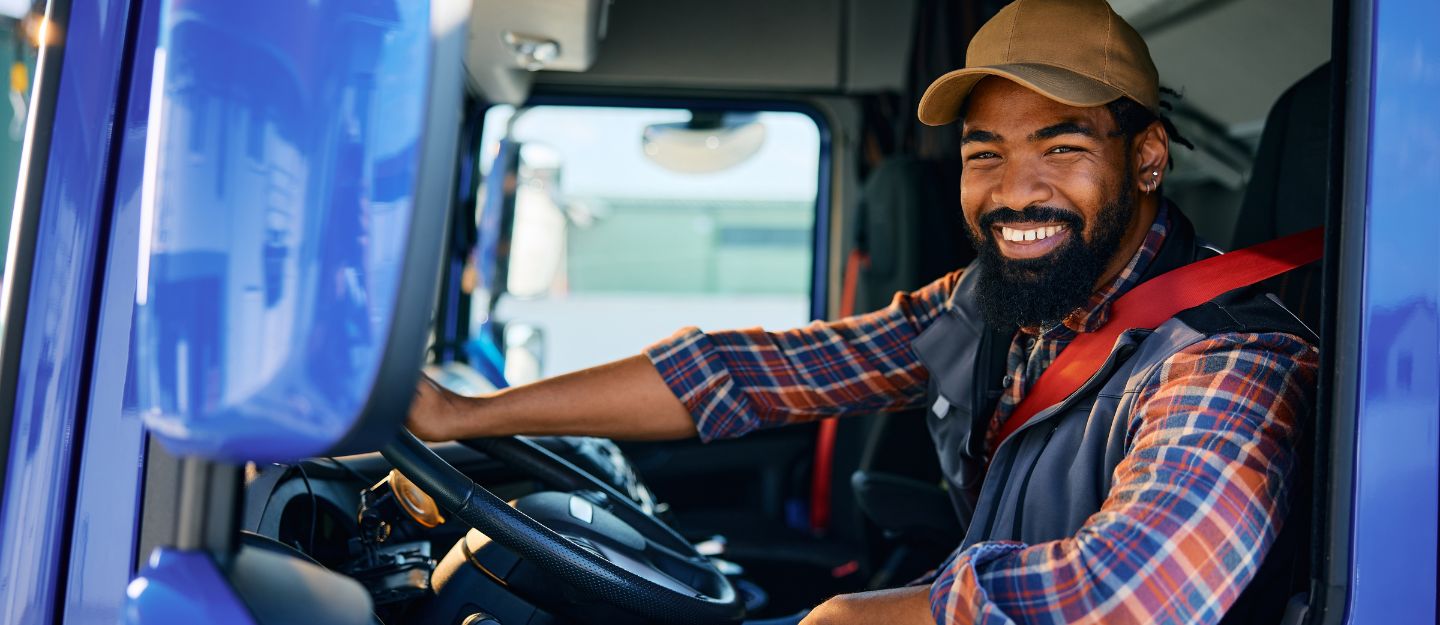 Smiling truck driver in the driver's seat, representing the journey to become a truck driver in Dubai.