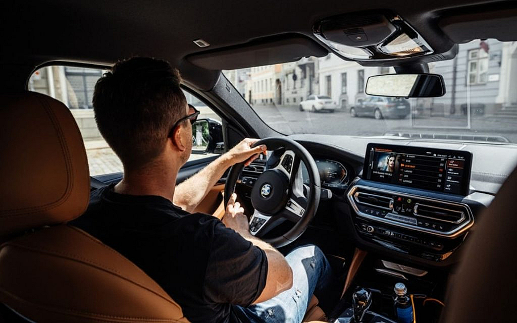 A man in black shirt driving  a latest BMW car
