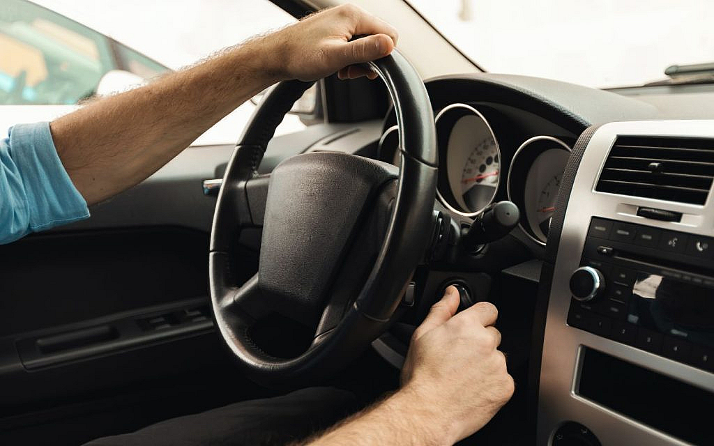 Man starting car engine after jump-start, ensuring proper battery charging time.