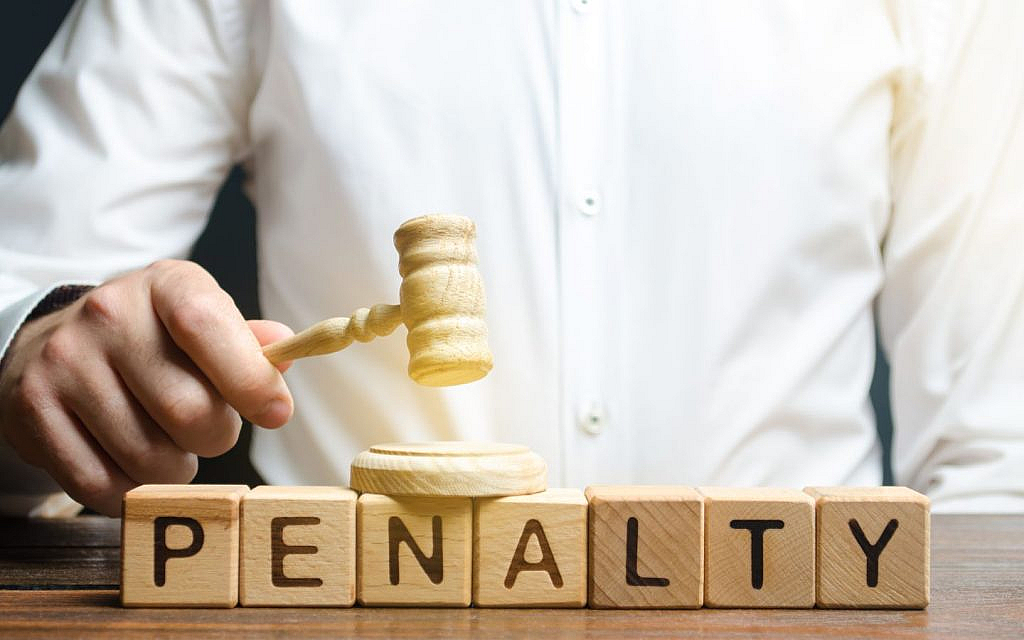 a judge’s wooden gavel placed next to colourful alphabet blocks spelling the word penalty.