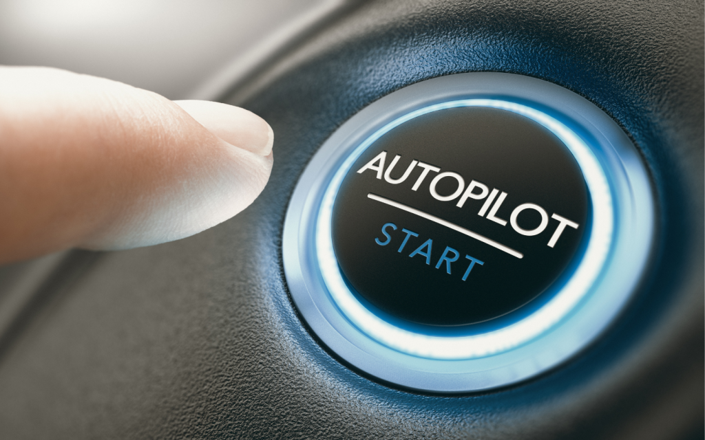 Finger pressing the Autopilot button in a self-driving car interface, indicating activation of autonomous driving mode. 