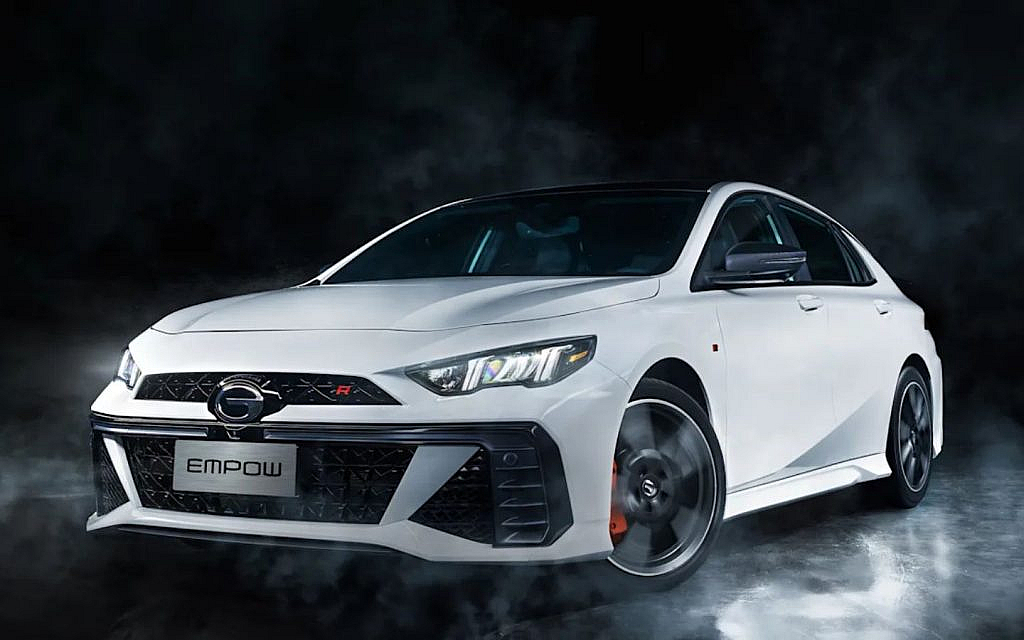 A white GAC Trumpchi Empow sport sedan with a black roof and red accents, against a dark, smoky background.
