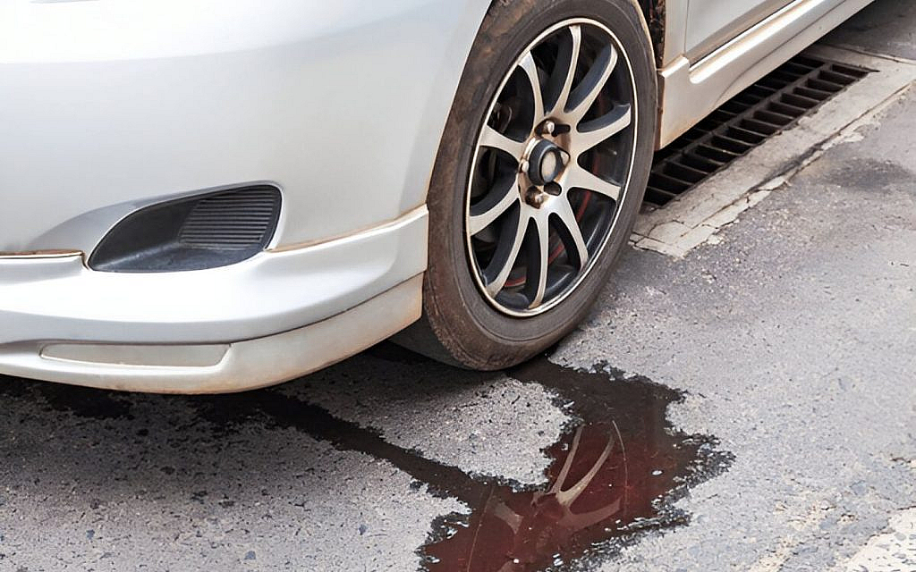 A white car parked on the road with water leaking from it