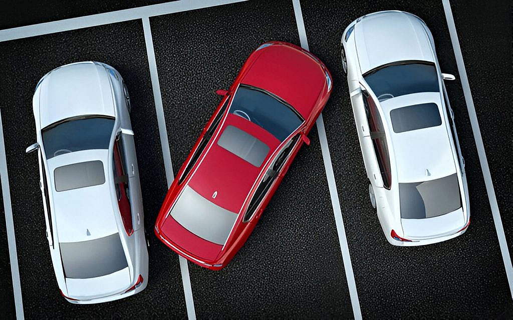 A red car is parked the wrong way in between two grey cars