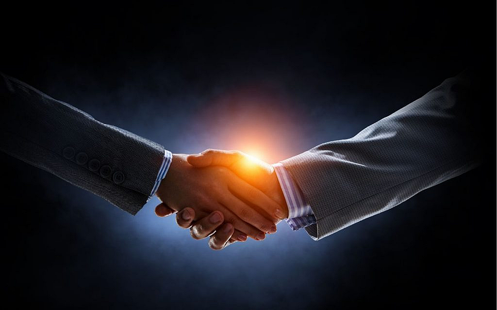 Two people shaking hands with a bright light emanating from their clasped hands.