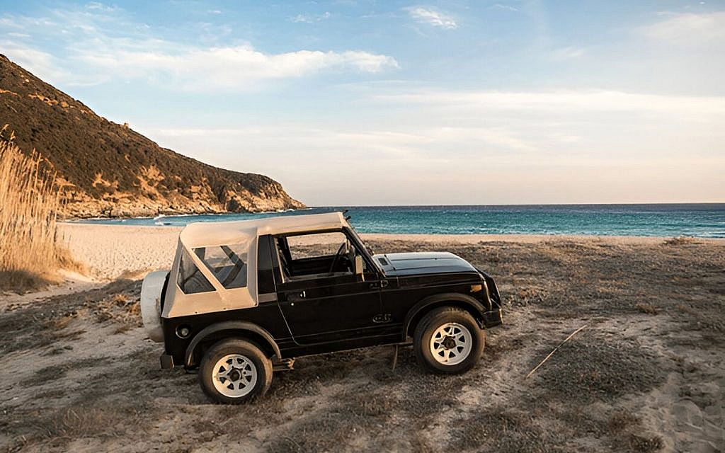 A black off-roader at the edge of mountain overlooking sea
