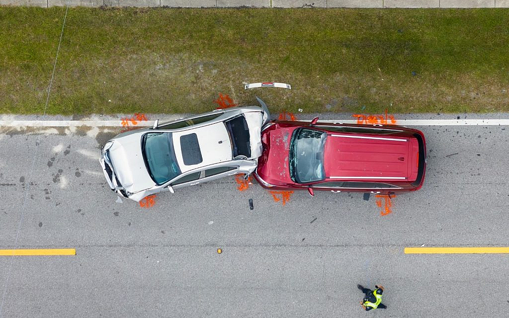Aerial view of a car crash between a silver sedan and a red SUV.