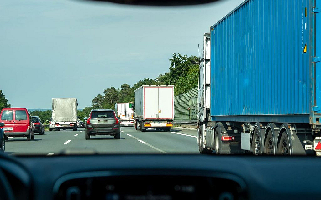 View from a car on a multi-lane highway, with multiple trucks and cars ahead