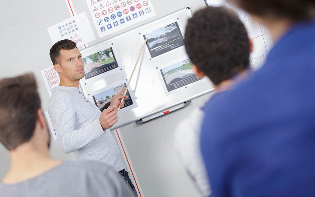 مدرب قيادة يشرح نظريًا لمجموعة من الطلاب