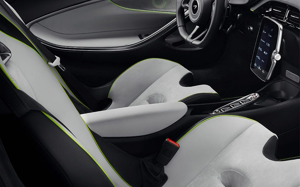Interior of a modern sports car, showing white and black seats with green accents and a digital dashboard.
