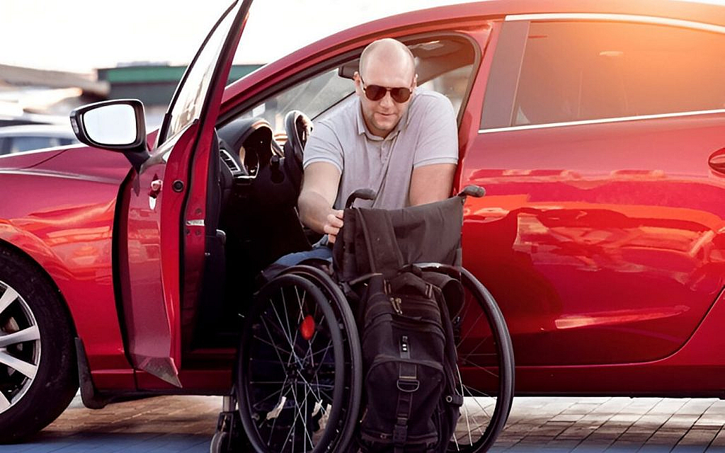 A people of determination driving a red car