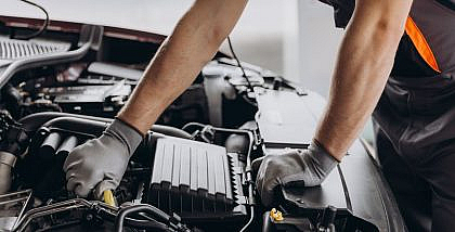 A Mechanic's gloved hands working on a car engine, illustrating vehicle low maintenance.