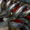 Close-up of a shiny chrome exhaust manifold or header bolted to an engine block.