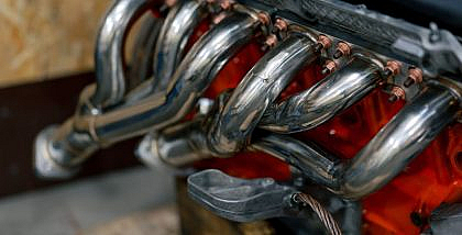 Close-up of a shiny chrome exhaust manifold or header bolted to an engine block.