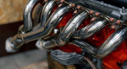 Close-up of a shiny chrome exhaust manifold or header bolted to an engine block.