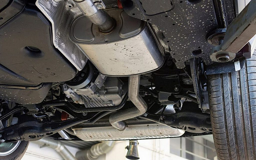Underbody view of a car on a lift, showing the exhaust system, muffler, and suspension components.