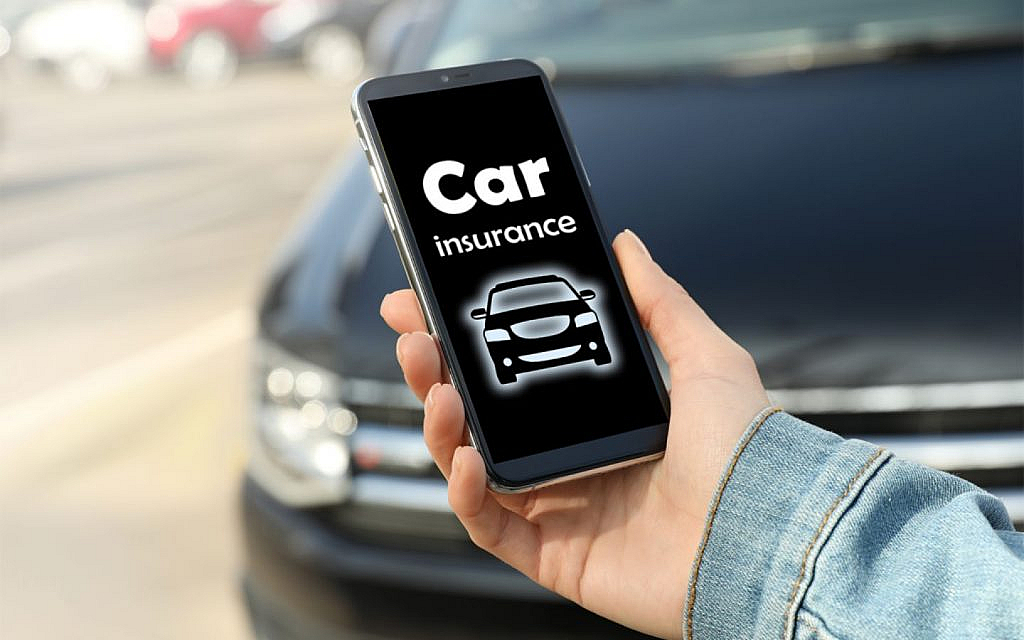 A hand holding a phone displaying "Car insurance" and a car icon, with a blurred car in the background.
