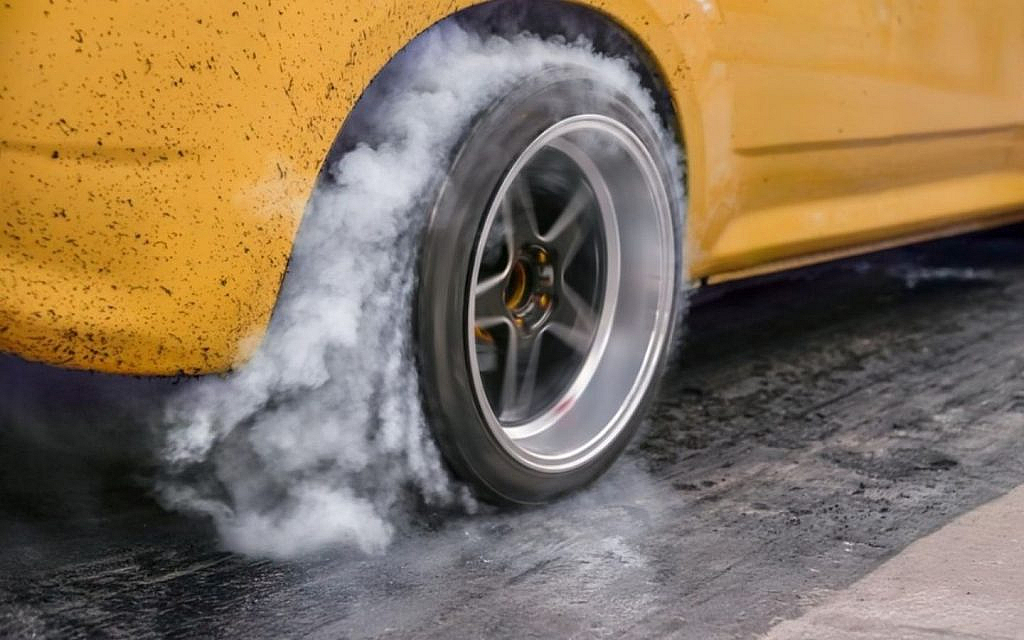 A yellow car dragging tyre releasing smoke