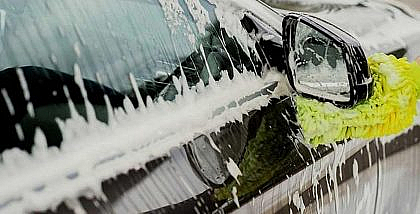person cleaning car with two-bucket car washing method