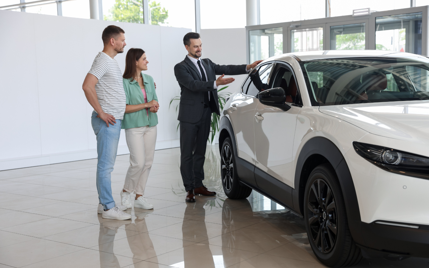 موظف مبيعات في معرض سيارات يشرح للزبائن مواصفات سيارة مازدا
