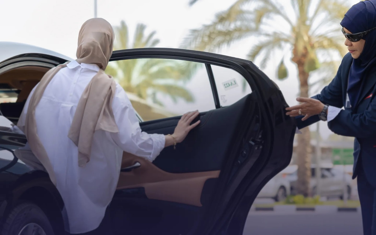 سائقة تفتح باب السيارة لراكبة 