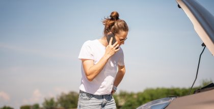 سيدة تقف أمام سيارة متعطلة