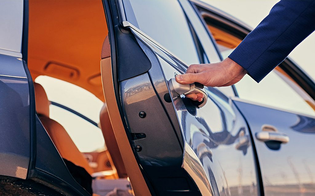 A person opening a door of a luxury car