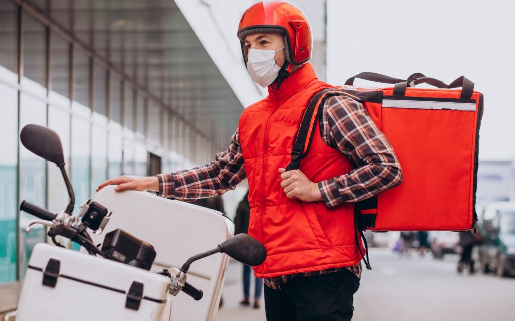 A rider standing with his delivery bike