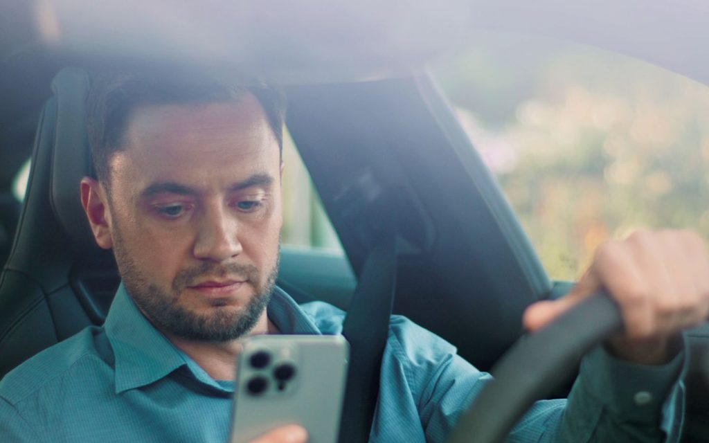 Man checking an emergency traffic alert on his phone while driving.