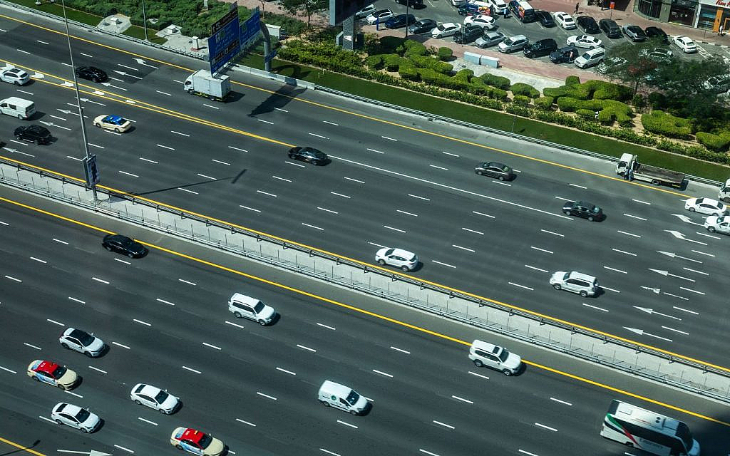 A bustling multi-lane thoroughfare in Dubai features a mix of cars and buses.