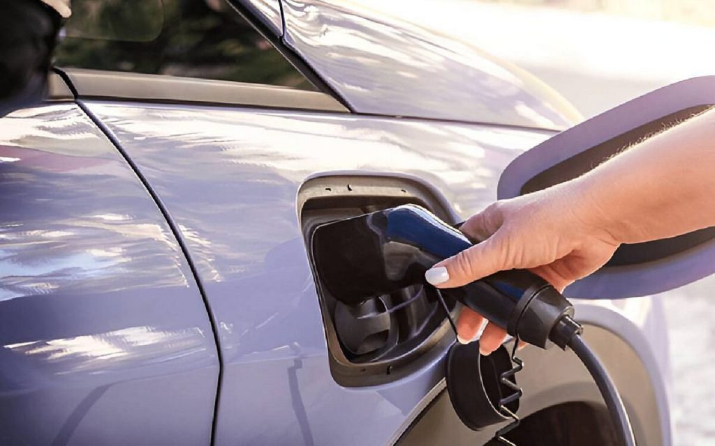 A car with an electric powertrain plugged into a charging station