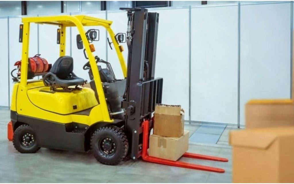 A yellow and black forklift is parked in a modern warehouse.